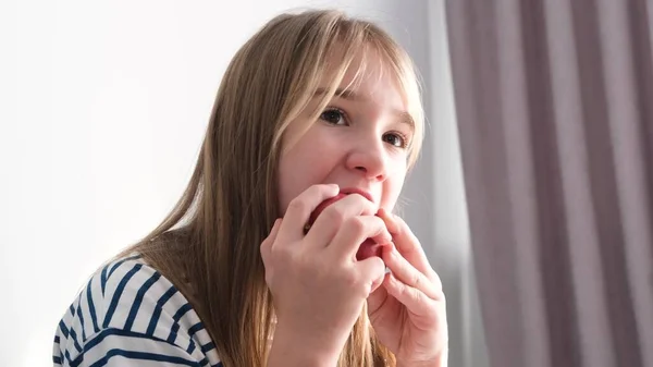 Child girl blonde eats an apple on a white background. Video Delicious ripe autumn fruits. Vegetarianism in children