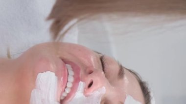 Güzellik salonunda ya da kaplıcada profesyonel bir kozmetik uzmanının hizmetlerinden yararlanan genç, beyaz bir kadın. Dikey video