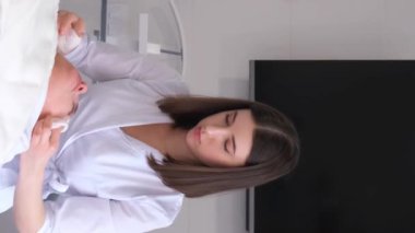 Kafasında havlu olan güzel bir kadın spa salonunda yüz masajı yaptırıyor. Lüks bir sağlık merkezinde cilt bakımı. Dikey video