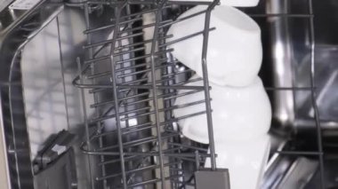 Bulaşık makinesinden bulaşıkları boşaltıyorum. Otomatik bulaşık makinesinde yıkanmış, parlak bulaşıklar. Dikey video
