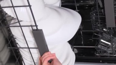 Bulaşık makinesinden bulaşıkları boşaltıyorum. Bir ev hanımı otomatik bulaşık makinesinden temiz bulaşıkları alır. Dikey video