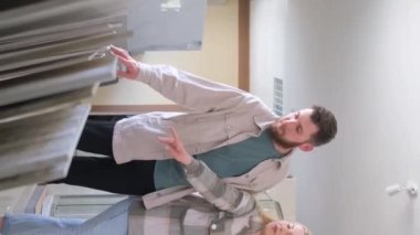 Genç bir çift, bir seramik dükkanındaki iç dekorasyon hakkında tezgahtarla konuşuyor. Seçim konsepti. Dikey video