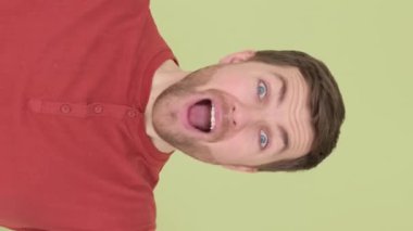 Avustralyalı bir adam: Yeşil arka plandaki yakışıklı adam kamerada izlenim bırakır ve güler. Dikey video