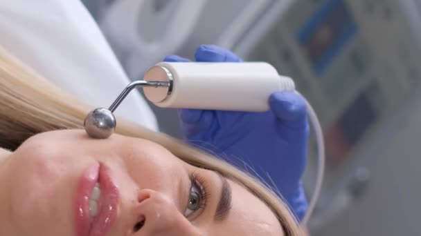 在微电流疗法中 年轻女性面部的特写 一个漂亮的女人在温泉诊所接受了一个刺激性的电 垂直录像 — 图库视频影像