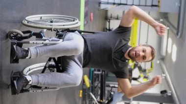 Tekerlekli sandalyede jimnastik yapan bir adamın dikey videosu. Yaralanmadan sonra rehabilitasyon süreci. Dikey video
