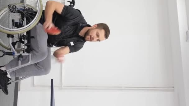 車椅子に乗っている若者が卓球をする ラケットを持ったゲーム スポーツ趣味 バーティカルビデオ — ストック動画
