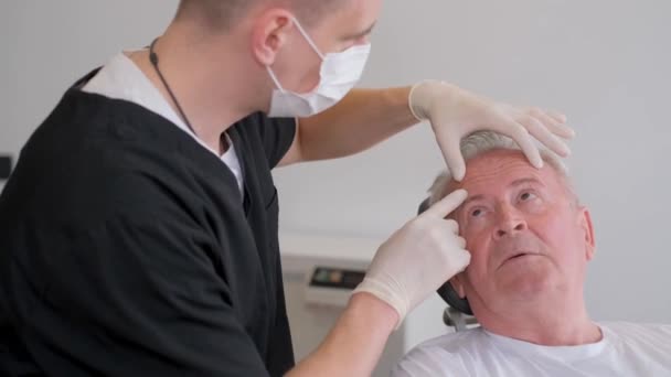 一位年轻的整形外科医生建议一位老年病人 一位退休人员 做面部手术 防止皮肤老化 — 图库视频影像