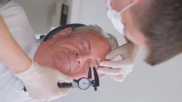 一个整形外科医生检查眼部下垂的皮肤并用口径仪测量的垂直录像 整形外科医生会诊 — 图库视频影像