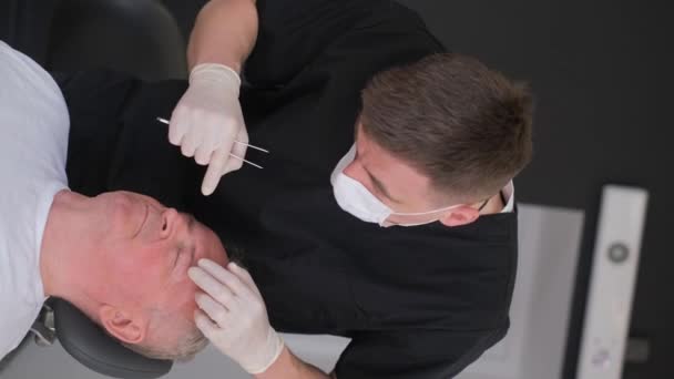 垂直录像 在手术室里 一位整形外科医生在动手术前检查了一位老人的脸 整形外科医生会诊 与老龄化作斗争 — 图库视频影像