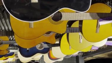 Bir enstrüman dükkanında sergilenen klasik gitarlar. Müzik aletlerinde indirim var. Dikey video