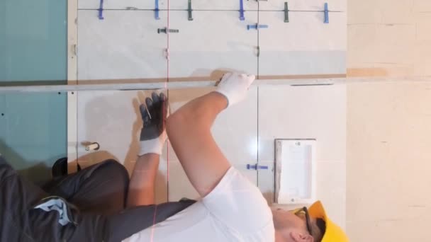 Egy Biztonsági Sisakos Építész Ellenőrzi Fürdőszoba Csempéinek Egyenletességét Egy Építőmunkás — Stock videók