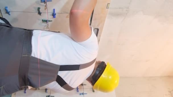 一位穿着工作服的建筑商正在浴室里安装瓷砖 修理一栋新楼 垂直录像 — 图库视频影像
