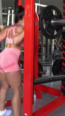 Sporcu kız spor yapıyor spor yapıyor, spor yapıyor ve spor yapıyor. Spor salonunda halterle spor yapan sporcu bir kadın. Dikey video