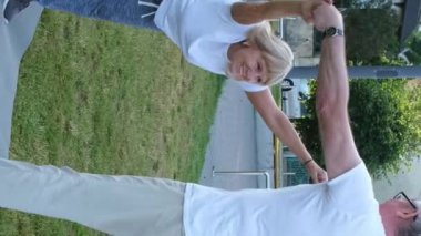 Kıdemli çift sabahları yaz parkında spor yapıyor. Emekliler, sağlıklı yaşam tarzı. Dikey video