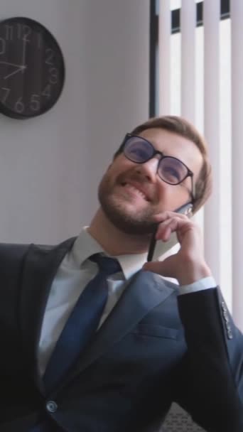 편안한 의자에 앉아있는 전화로 말하는 성공적인 매력적인 관리자 사무실에서 전화에 — 비디오