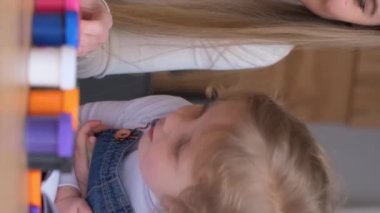 Güzel bir anne kızına akrilik boyalarla resim yapmayı öğretir. Evde eğleniyorlar. Mutlu aile birlikte vakit geçiriyor. Dikey video