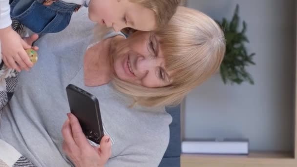 祖母と孫はスマートフォンを使い 一緒に楽しんでいます バーティカルビデオ — ストック動画
