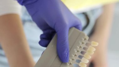 Dişçi randevusundaki genç esmer kız. Beyaz diş implantı kurulumu. Bir dişçinin işi. Dikey video