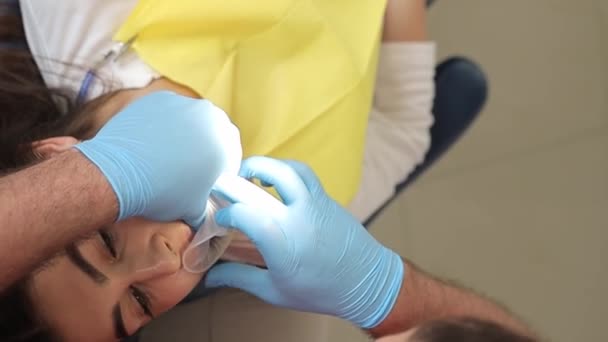 歯科医は現代の方法を使用して歯を白くします 歯の治療とホワイトニング バーティカルビデオ — ストック動画