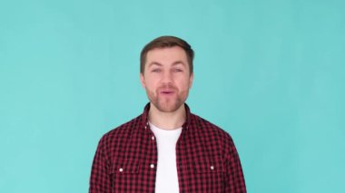 Renkli bir stüdyoda kameraya bakan yakışıklı, gülümseyen genç bir adamın portresi. Adamın biri mavi arkaplanda 