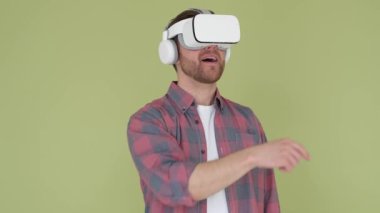 İzole edilmiş arka planda sanal gerçeklik gözlüğü takan yakışıklı adam ürünü sunmak için elleri ile ekranı çeviriyor. Sanal teknolojiler