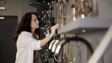 Kadın müşteri ev eşyaları mağazasında duş almayı tercih ediyor. Çekici bayan müşteri mağazadaki banyo musluklarını deniyor.. 