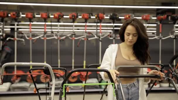 Una Mujer Joven Elige Una Cortadora Césped Una Tienda Mejoras — Vídeo de stock