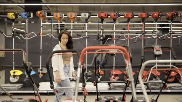 여자는 하드웨어 상점에서 기계의 거대한 선택의 자신의 마당을 돌보는 — 비디오