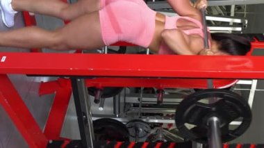 Sporcu kız spor yapıyor spor yapıyor, spor yapıyor ve spor yapıyor. Spor salonunda halterle spor yapan sporcu bir kadın. Dikey video