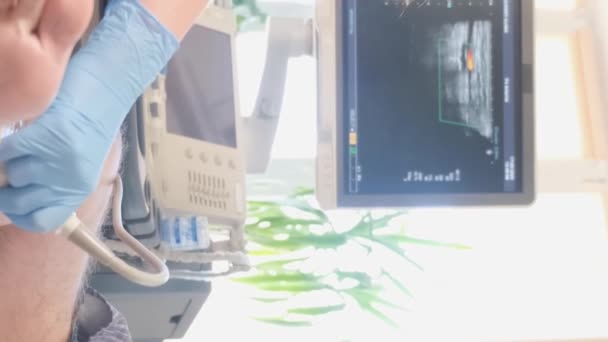 女性の医師は 患者の膝のX線を撮影するためにソノグラフィを使用しています 高齢者の足の治療 バーティカルビデオ — ストック動画