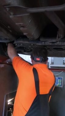 Araba bir araba atölyesinde araba tekerleklerini ayarlamak için ayakta duruyor. Dikey video.