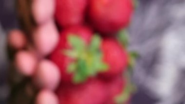 Erkeklerin elindeki bir demet olgun çileğin makro videosu. Arka plan bulanık. Çiftlikte çilek hasadı. Bir sürü çilek var. Dikey video