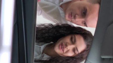 Mutlu genç bir aile lüks bir araba satın alır. Araba satış müdürü yeni bir araba gösteriyor. Araba satış konsepti. Dikey video