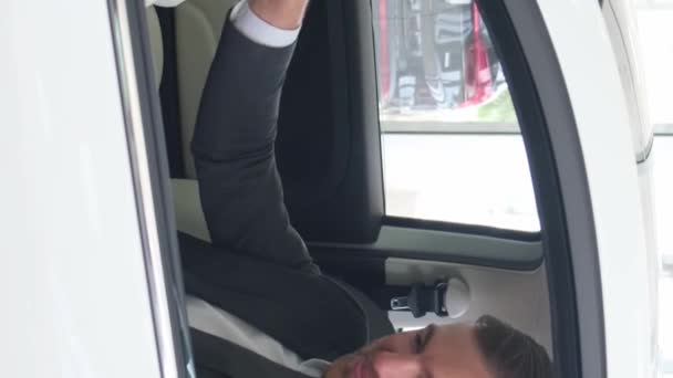 男はディーラーで新しい電気自動車に座り 新しい車の購入を祝います 車を買った 自動車販売コンセプト バーティカルビデオ — ストック動画