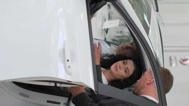 一个快乐的年轻家庭会买一辆豪华车 汽车销售经理展示一辆新车 汽车销售概念 垂直录像 — 图库视频影像