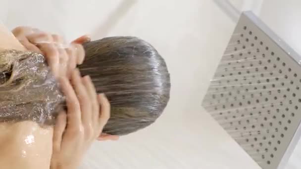 シャワーで楽しんでいる美しい若い女性 彼女はシャワーで髪を洗っている リアビュー バーティカルビデオ — ストック動画