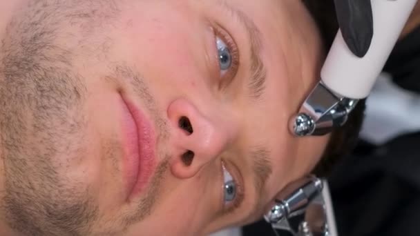 잘생긴 남자를위한 마사지 화장품 전문가는 현대적인 장치를 사용하여 얼굴에 마사지를 — 비디오