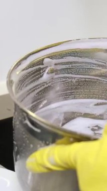 Bir kadın metal bir tavayı yıkıyor. Günlük ev işi kavramı.