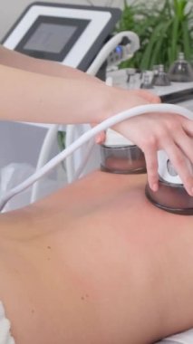 Süpürge vücut masajı, güzellik salonunda genç bir kadın. Selülit sorunlu bölgelerin tedavisi için güzellik salonunda bir anti-selülit paten-vakum masaj yöntemi mevcuttur. Dikey video