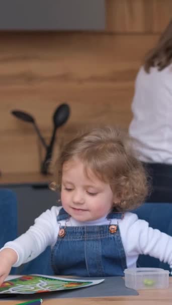 Uma Jovem Mãe Lava Pratos Cozinha Uma Criança Pequena Brinca — Vídeo de Stock