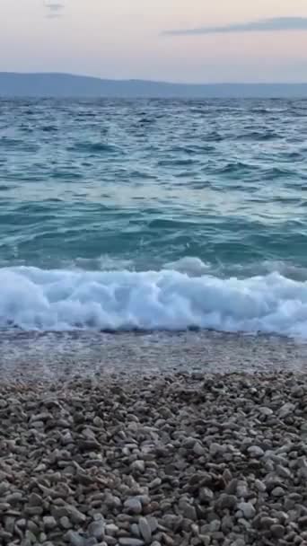 海岸に衝突する美しい波 海は青い水で泳いでいる バーティカルビデオ — ストック動画
