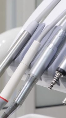 Diş sandalyesindeki diş aletlerinin yakın plan görüntüsü. Dişlerle çalışmak için steril, metal aletler. Diş tedavisine modern yaklaşımlar. Dikey video