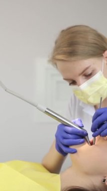 Dişçi, dişçi kliniğinde tedavi görüyor. İnsanlar, tıp, stomatoloji ve sağlık hizmetleri kavramı. Diş hekimi bir hastaya diş tedavisi yapıyor. Dikey video