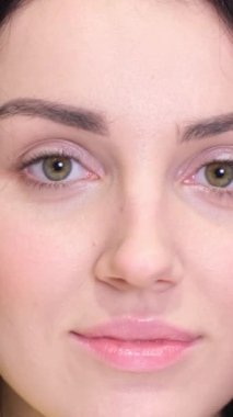 Güzel, gülümseyen esmer bir kadının portresi hafif arka planda kameraya bakıyor. Doğal güzellik kavramı. Dikey video