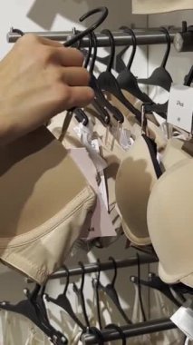 Genç bir kadın iç çamaşırı mağazasından sütyen alıyor. Mağazalardan alışveriş. Dikey video.
