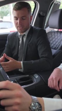 Bir araba galerisindeki bir satıcı müşteriye ABD 'de yeni bir arabanın içini gösteriyor. Yeni araba galerisi. Dikey video