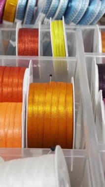 Tekstil dükkanında farklı renklerde hediye kurdeleleri. Ağır çekim. Dikey video.