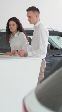 Evli bir çift araba galerisinden bir araba satın alma emri imzalıyor. Bir araba satıcısı yeni bir araba almak için bir çiftle konuşuyor. Dikey video
