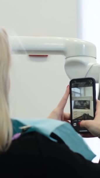 Sarışın Bir Kadın Hasta Dişçi Koltuğunda Otururken Akıllı Telefonuyla Dişlerinin — Stok video