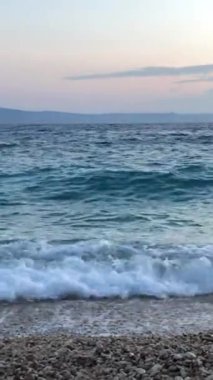 Deniz dalgaları deniz kıyısına çarpıyor. Fırtına sırasında dalgalar çakıl taşı plajına vurur. Denizde fırtına. Denizde dinlenme kavramı. Dikey video